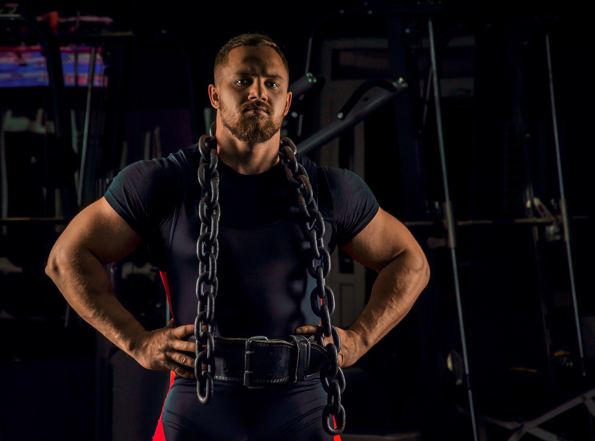 handsome athlete with chain around his neck stands gym looks straight ahead