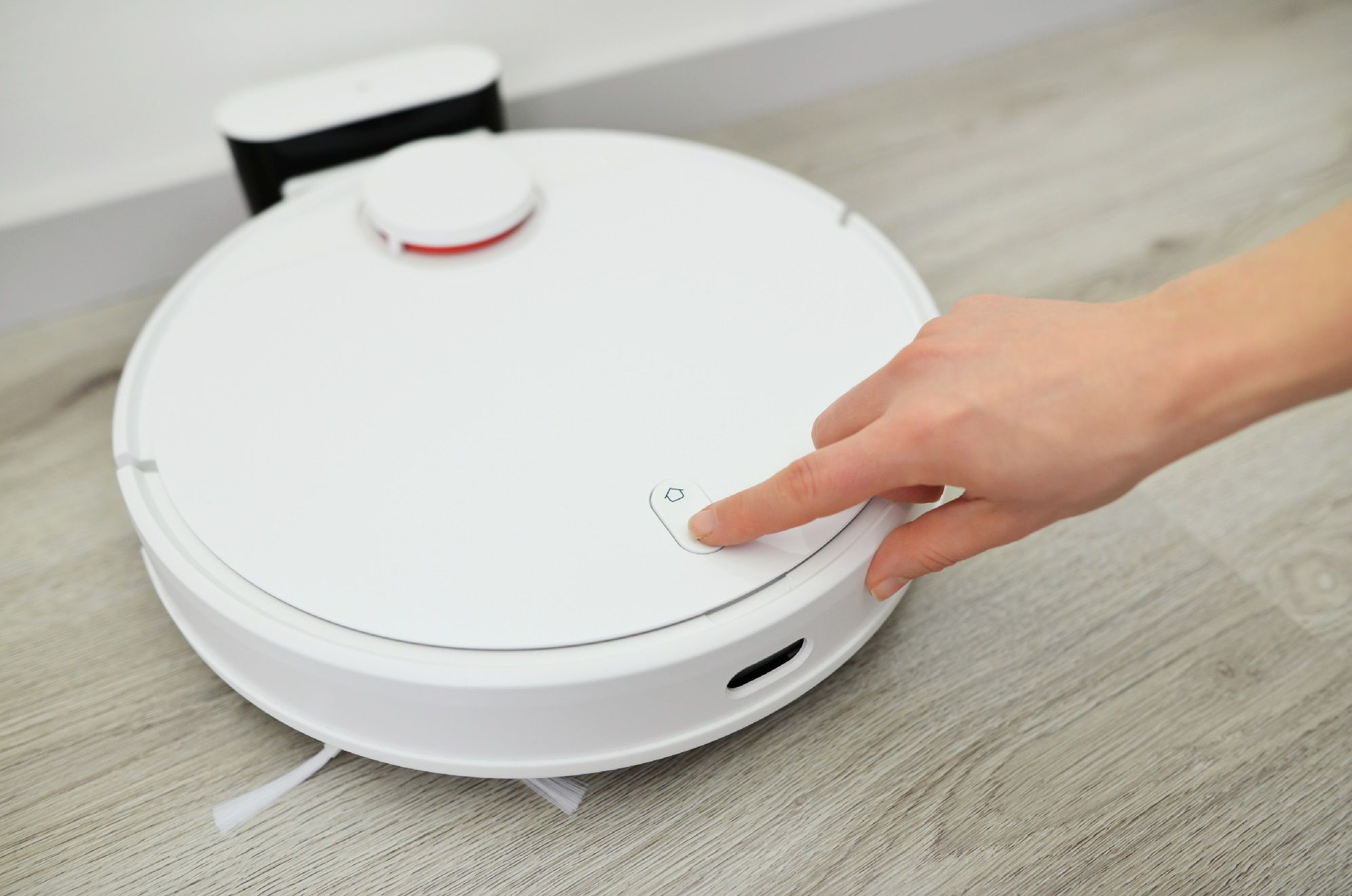 kvinna trycker robotdammsugare