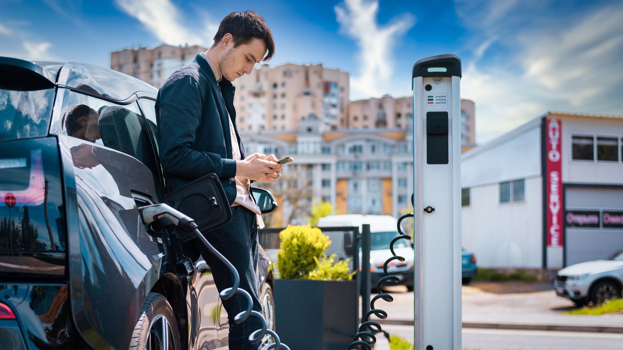 man charging his electric car charge station using smartphone