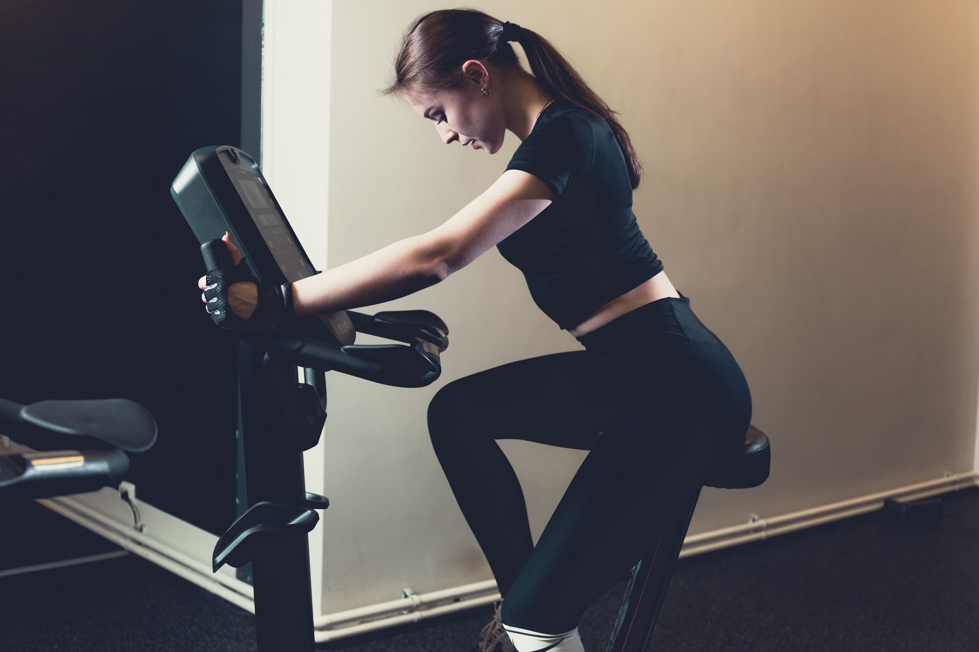 side view young woman riding exercise bike