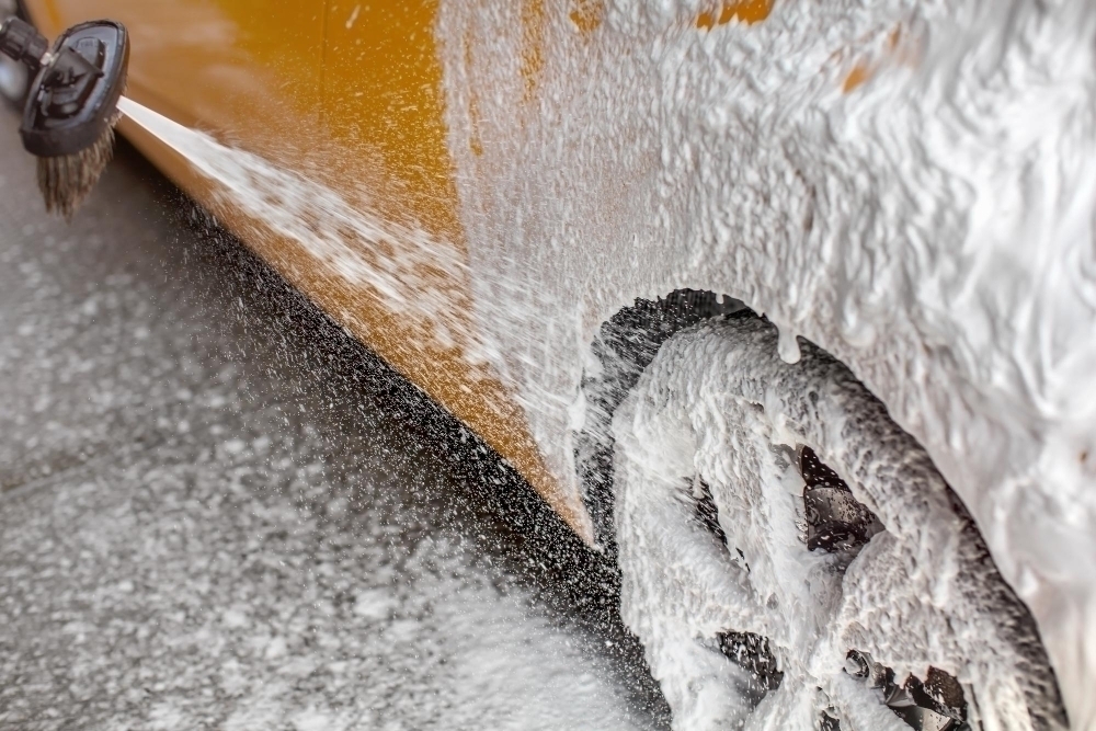 white shampoo foam sprayed car rear wheel side when washed carwash