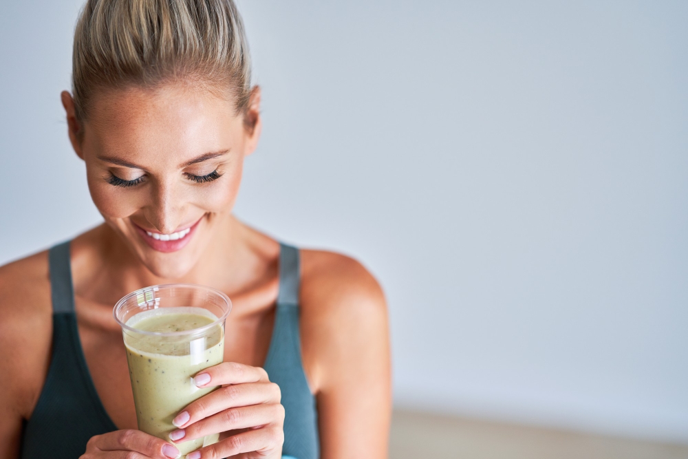 Adult woman drinking healthy smoothie after workout