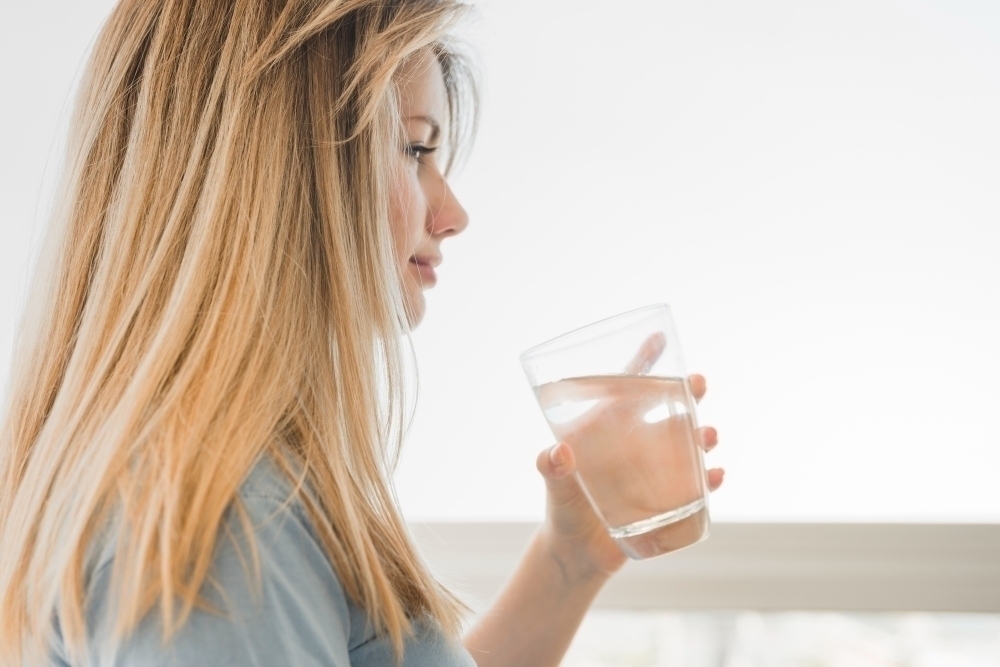 Blonde girl holding glass of water