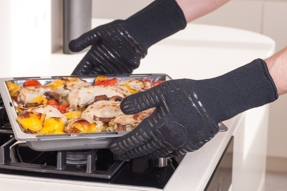 Chef removes the hot tray from the oven in protective gloves