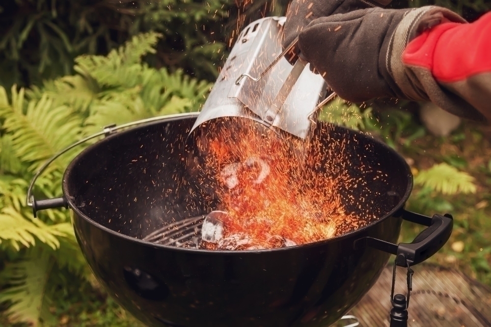 Close up man with gloves chimney starter barbecue grill