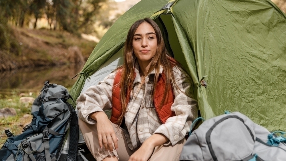 Happy hiking girl in the forest sitting in the tent front view