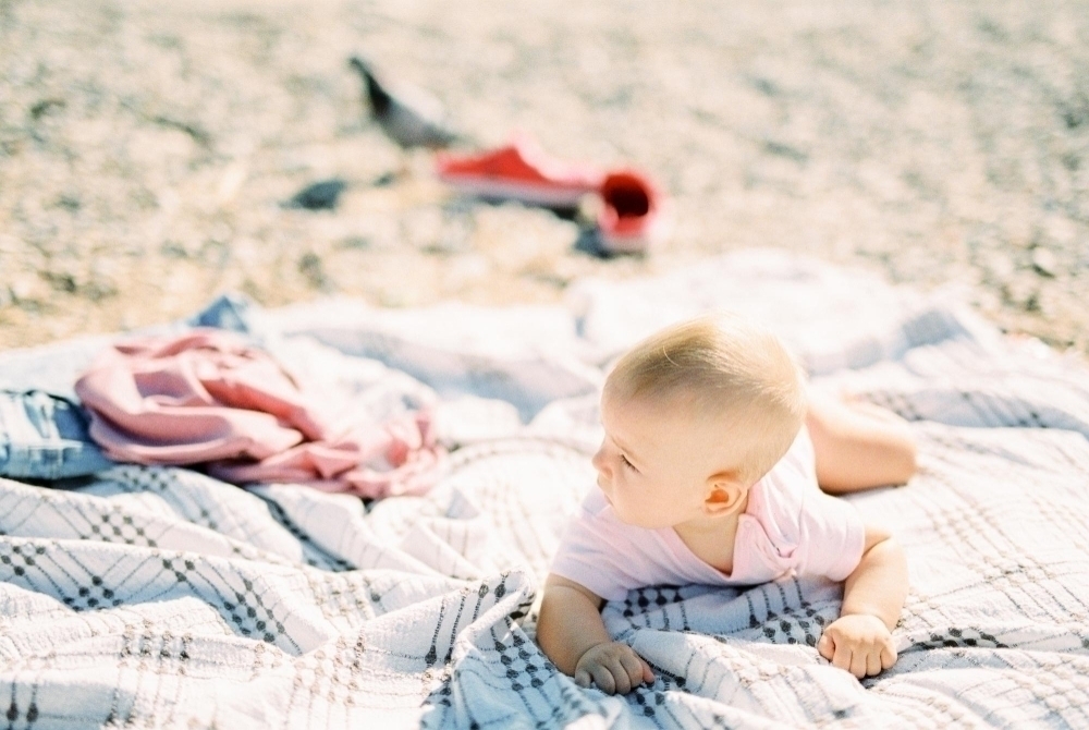 High angle view of baby lying on blanket at beach