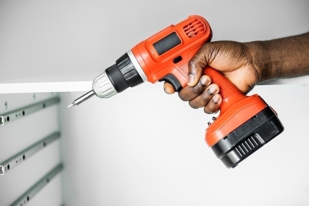 Man using electronic screwdriver to install cabinet