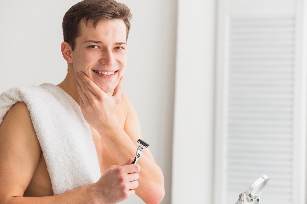 Shaving concept with attractive young man with razor
