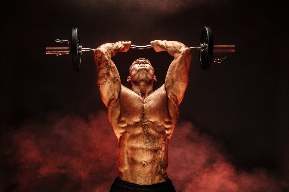 Strong sportsman lifting heavy dumbbell in smoke