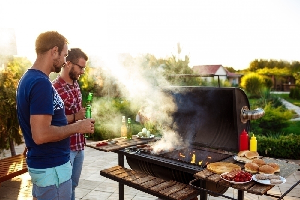 Tva maen grllar mat pa en gasolgrill