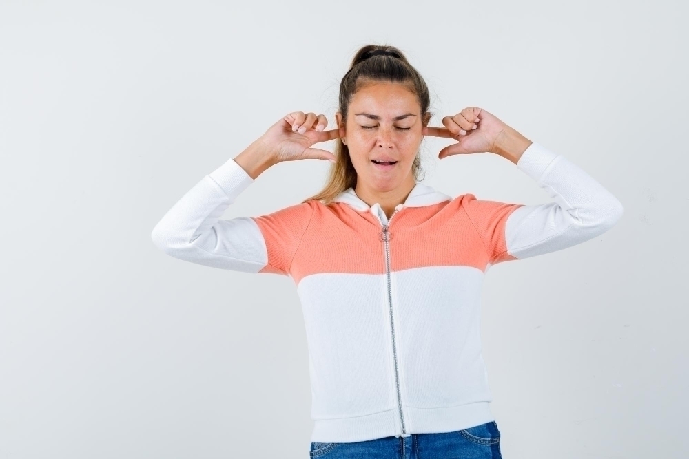 girl covering her hears in lack of ear plugs