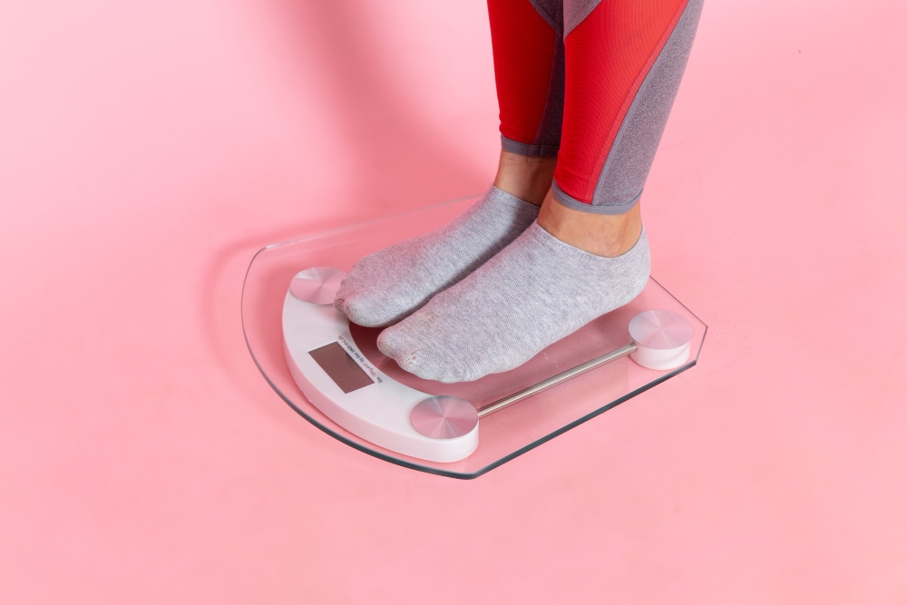 young female measuring her weight digital scale